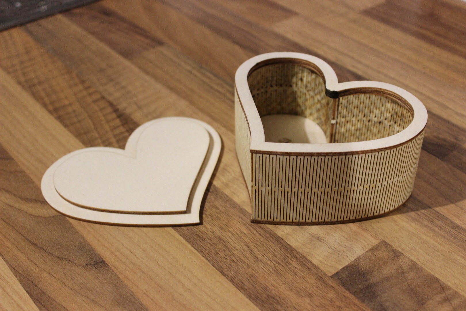 a laser cut heart shaped box and lid, both made of plywood, sitting on a table