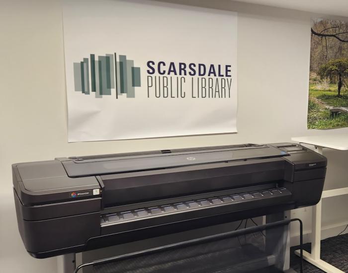 The poster printer against the wall under a Scarsdale Library poster